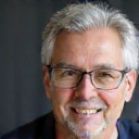 Ritratto professionale di un uomo sorridente, capelli grigi, occhiali